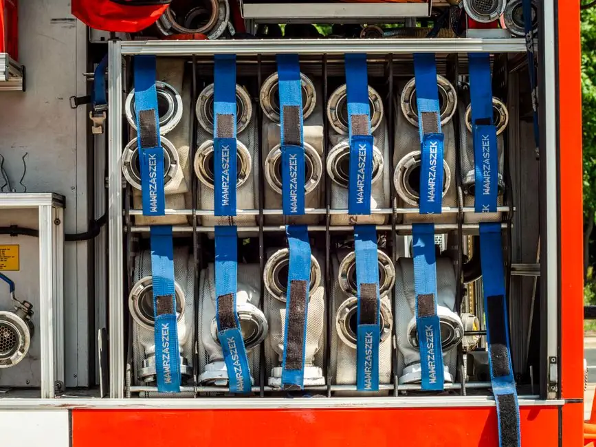 Close-up of fire truck hose storage with blue straps and equipment neatly organized.