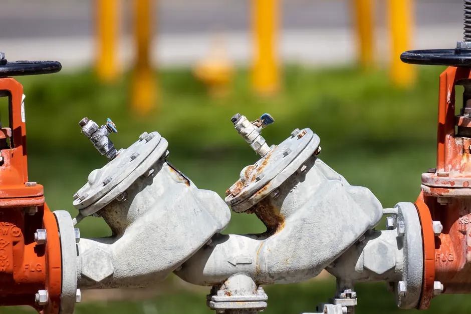 Detailed view of rusted industrial gas valves outdoors on a sunny day.